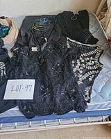 Pile of assorted women’s garments including sequined black top, labelled Lot 97