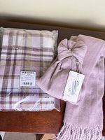 Both scarves shown; plaid sealed, solid rolled with bow and tag visible