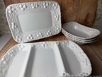 All five white embossed ceramic serving pieces: large platter, divided platter, three small trays