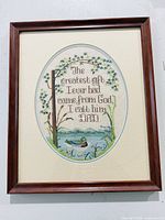 Full view of framed cross-stitch showing text, scene, frame, mats