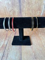 Five bracelets displayed on black stand