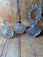 Group view of three vintage cut/pressed glass perfume bottles