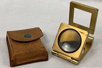 Magnifier folded open next to leather case