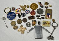 Full assortment laid out showing all pins, tokens, money clip and keychain