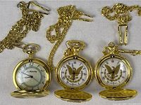 All three gold-tone pocket watches open with chains visible