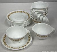 Stack of 12 saucers, 9 stacked cups, and creamer front