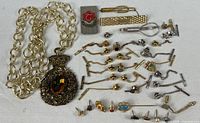 Full lot showing necklace, tie clips and rows of tie tacks