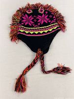 Full view of beanie showing fringe mohawk, ear flaps, braided tassels