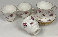 Group view: three upright cups, one tipped cup showing exterior pattern, stack of four saucers