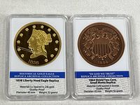 Front view of both replica coins in holders showing obverse designs and specification labels