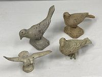 Group of four cast iron bird figurines showing sizes and paint finishes