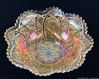 Oblique view of iridescent marigold carnival glass bowl showing pattern and scalloped rim