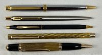 Five writing instruments laid out horizontally