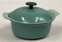 Side view of turquoise enameled cast iron casserole with lid and handles