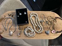 Overview of lot displayed on wooden board: necklaces, pendants, pearl strands, earrings
