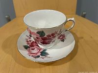 Teacup on saucer showing floral design and gold trim