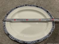 Top view of oval platter with measuring tape showing about 40 cm length and blue border design