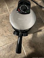 Closed waffle maker showing brand on lid and control dial