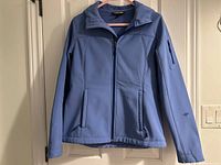 Front view of light blue softshell jacket on hanger