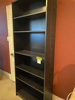 Full view of tall black-brown bookcase with five shelves