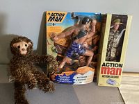 All five items displayed: two Action Man figures, Smart Ball package, straw monkey, baseball scroll partially visible