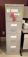 Front view of gray 4-drawer filing cabinet showing handles, label holders, and lock