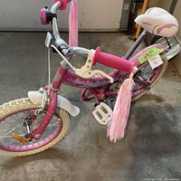 Oblique front view showing pink frame, white tires, tassels, front brake