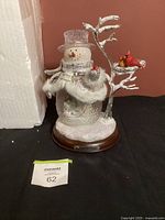 Full view of lighted musical snowman decoration with tree and cardinals on base