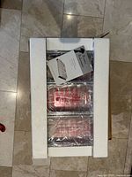 Box interior showing three stainless steel pans wrapped in plastic with foam protectors