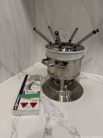 Front view of fondue set assembled with forks inserted and fire gel pack beside