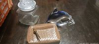 glass dolphin figurine, square glass jar, tan wallet closed