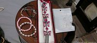 Overall lot showing cord bracelets, bead bracelets, boxed rhinestone butterfly hair comb, and bagged floral stud earrings