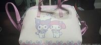 Front of purse showing My Melody & Kuromi graphic, top handles, strap attachments