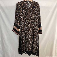 Front view of black floral kaftan on hanger