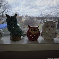 All three ceramic owl figurines displayed on windowsill