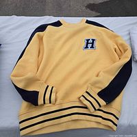 Full view of yellow sweater with navy accents and H patch