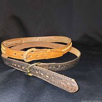 Both leather belts coiled, showing buckles and overall appearance