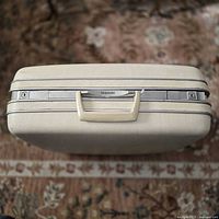 Closed suitcase top showing handle, latches, logo
