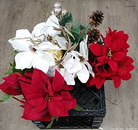Top view of three faux floral stems: two red poinsettias and one white amaryllis with pinecones and glitter accents