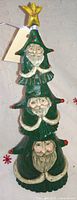 Front view of carved wooden Christmas tree totem with four Santa faces and star topper