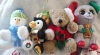Four small hanging plush figures—snowman, penguin, teddy bear, grey bear