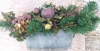 Front view of galvanized planter with artificial evergreen sprigs, glittered faux fruits, leaves and twigs