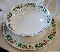 Top view of bowl nested on platter showing holly berry rim and gold trim