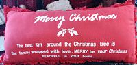 Front of red lumbar pillow showing white Merry Christmas text and fringe