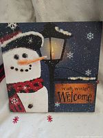 Front view of square LED canvas showing snowman, lamppost, and welcome sign