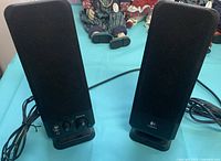 Front view of both Logitech speakers, showing controls and cables