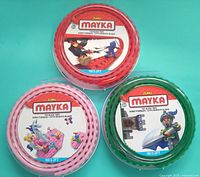 Front view of three sealed Mayka tape rolls in red, green, pink