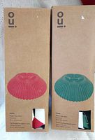 Two boxed Oui. paper tree skirts, red and green versions visible on packaging