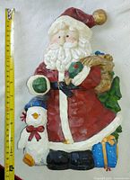 Full view of painted resin Santa wall plaque with measuring tape showing approx 14 in height