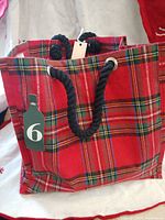 Front view of red plaid six-bottle tote with rope handles and bottle tag